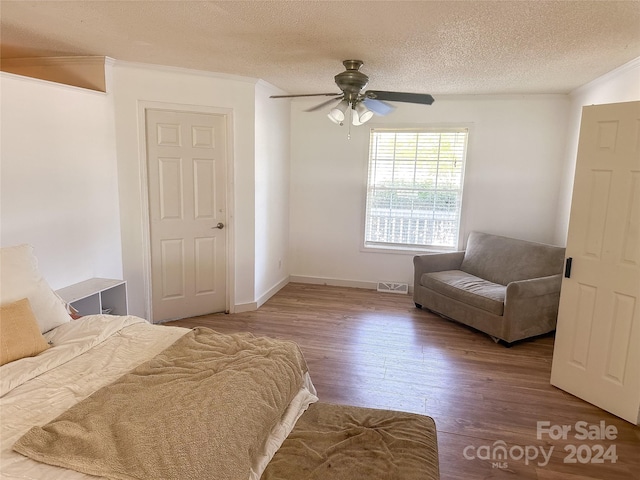 unfurnished bedroom featuring ceiling fan, ornamental molding, wood-type flooring, and a textured ceiling