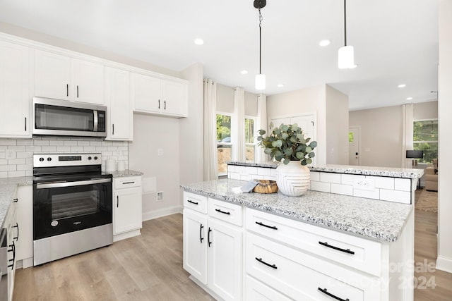 kitchen featuring a kitchen island, white cabinets, light wood-style floors, appliances with stainless steel finishes, and decorative backsplash