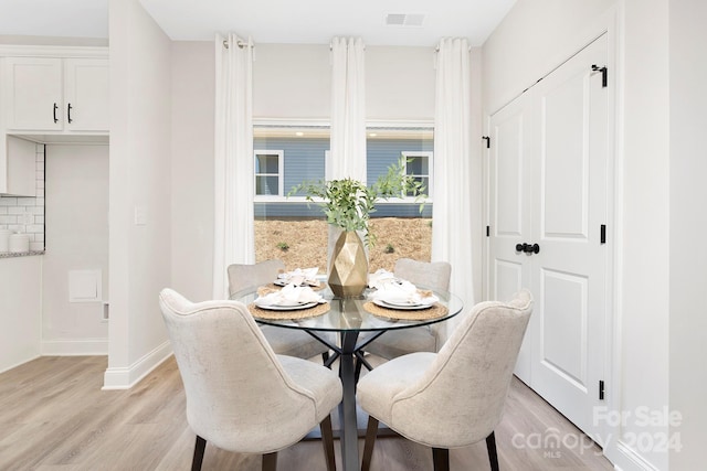 dining room with light wood-style floors, baseboards, and visible vents