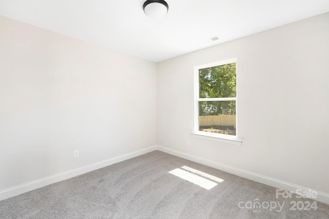 unfurnished room featuring carpet floors, visible vents, and baseboards