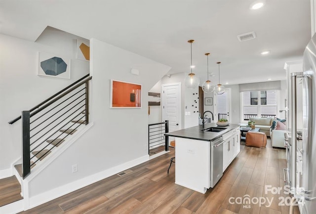 kitchen featuring sink, dark hardwood / wood-style flooring, an island with sink, white cabinets, and appliances with stainless steel finishes