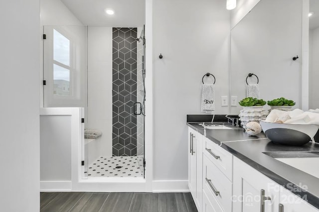 bathroom with hardwood / wood-style floors, vanity, and a shower with shower door