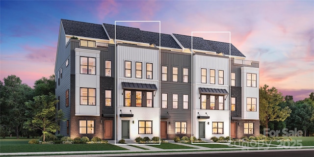 townhome / multi-family property featuring brick siding and a yard