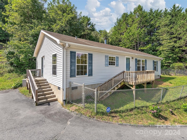 view of front of house with stairs, a deck, fence private yard, crawl space, and a front yard