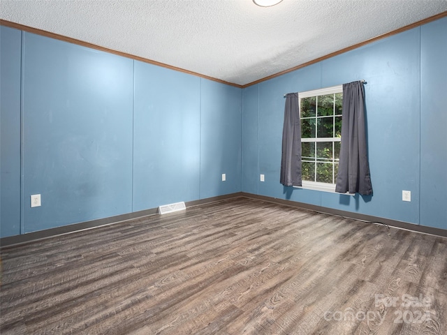 empty room featuring ornamental molding, a textured ceiling, wood finished floors, and visible vents