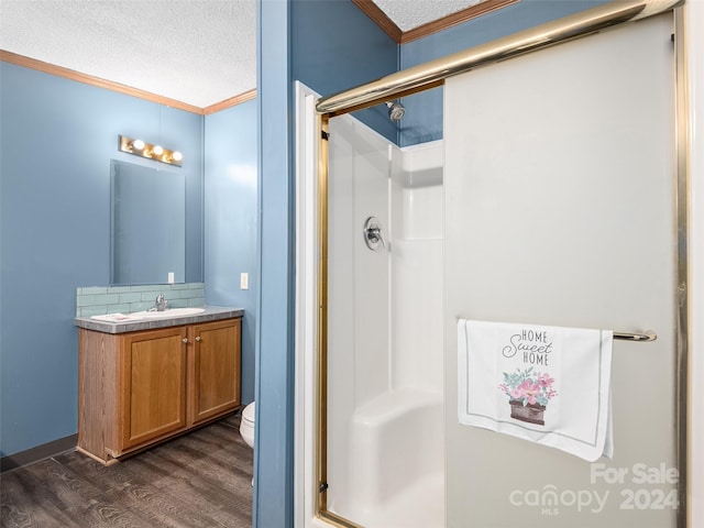 bathroom with a shower stall, wood finished floors, toilet, a textured ceiling, and crown molding