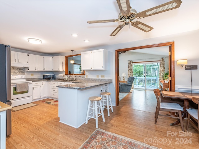 kitchen with kitchen peninsula, white cabinets, pendant lighting, and appliances with stainless steel finishes