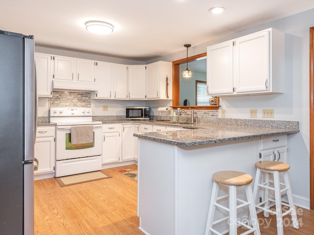 kitchen featuring a breakfast bar, white cabinets, light hardwood / wood-style flooring, kitchen peninsula, and stainless steel appliances