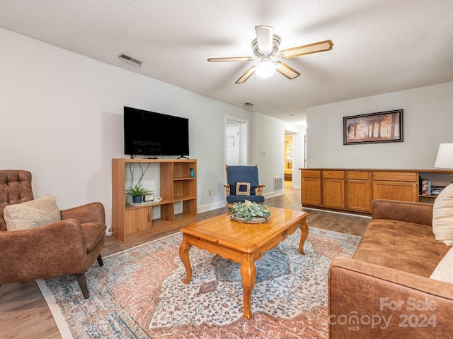 living room featuring ceiling fan, a textured ceiling, and light hardwood / wood-style flooring