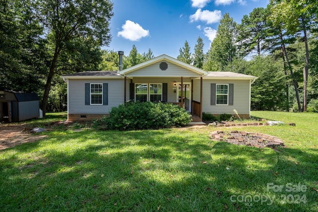 single story home with a storage shed, a front yard, and covered porch