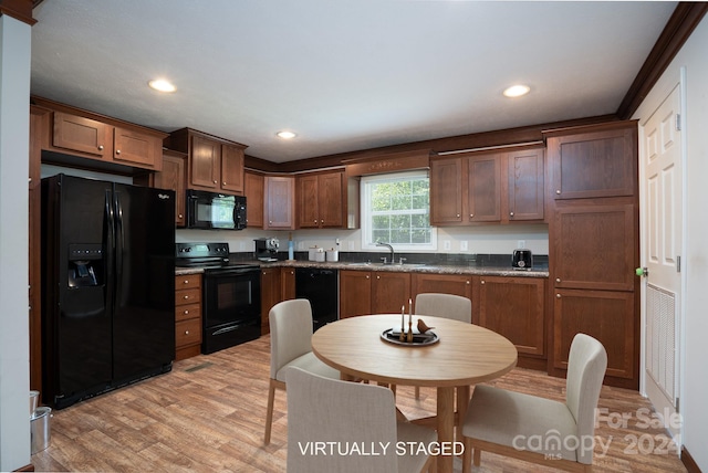 kitchen with dark stone counters, sink, light hardwood / wood-style flooring, and black appliances