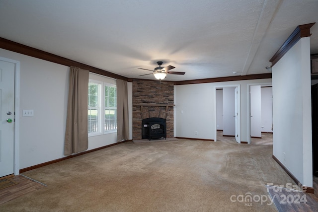 unfurnished living room with crown molding, a wood stove, ceiling fan, light carpet, and a brick fireplace