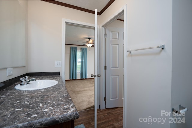 bathroom featuring ceiling fan, hardwood / wood-style floors, ornamental molding, and vanity