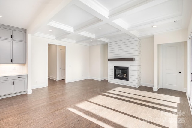 unfurnished living room featuring coffered ceiling, dark hardwood / wood-style floors, a fireplace, and beam ceiling