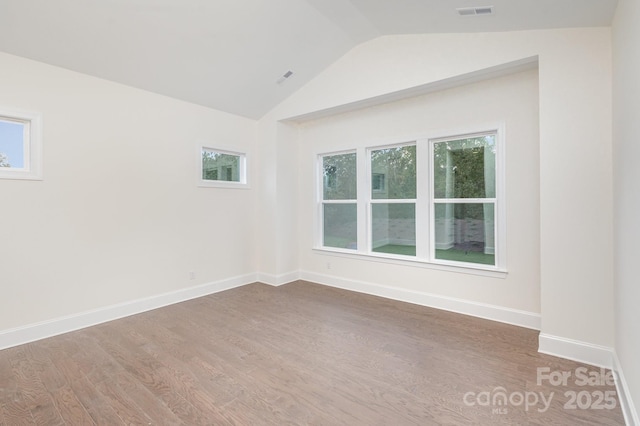 unfurnished room with lofted ceiling, wood finished floors, visible vents, and baseboards