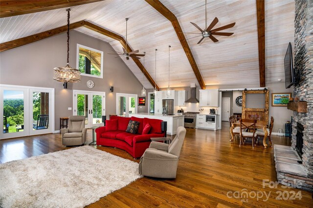 living room featuring a fireplace, beamed ceiling, high vaulted ceiling, ceiling fan with notable chandelier, and dark wood-type flooring