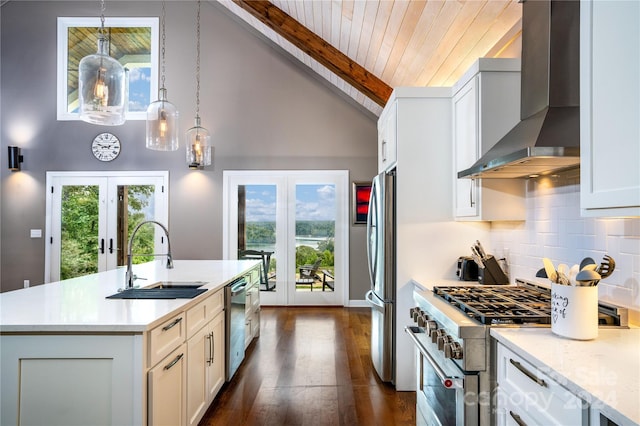 kitchen featuring french doors, stainless steel appliances, sink, wall chimney range hood, and a center island with sink