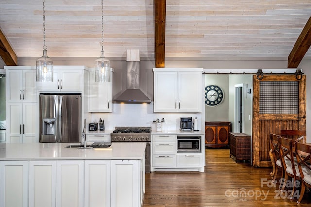 kitchen with beamed ceiling, wall chimney exhaust hood, appliances with stainless steel finishes, white cabinetry, and a barn door