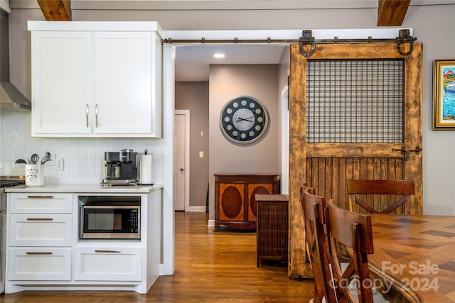 kitchen featuring a barn door, hardwood / wood-style floors, beam ceiling, and tasteful backsplash