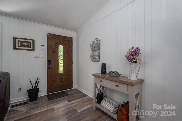 entryway with vaulted ceiling, crown molding, wooden walls, and dark hardwood / wood-style floors