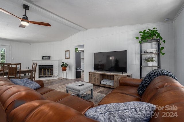 living room featuring wood-type flooring, vaulted ceiling with beams, a brick fireplace, and ceiling fan