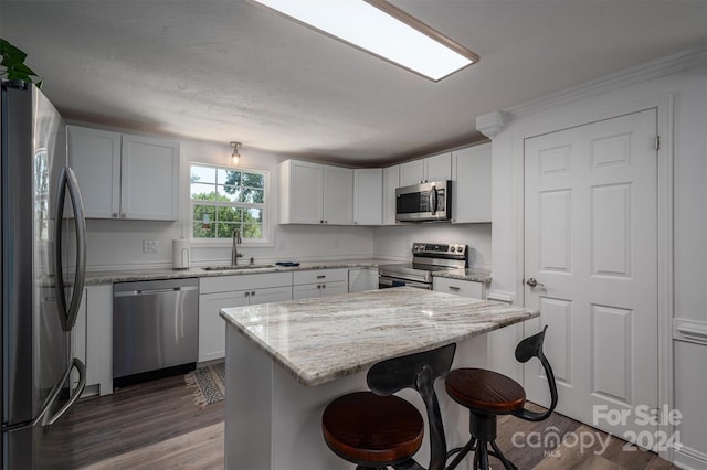 kitchen featuring appliances with stainless steel finishes, light stone counters, dark wood-type flooring, sink, and white cabinetry