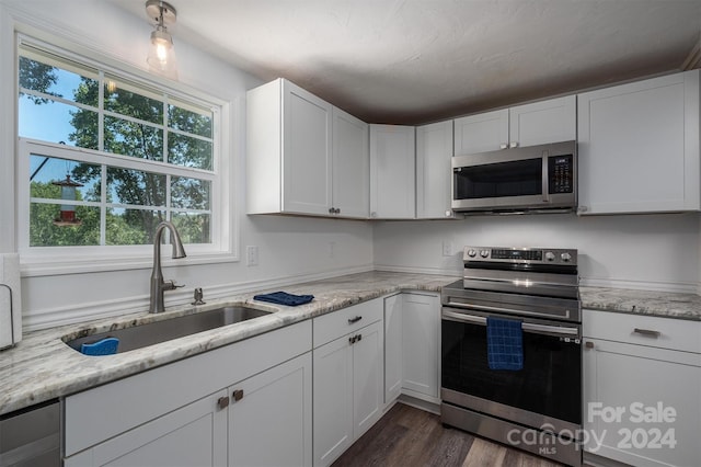 kitchen with white cabinets, sink, dark hardwood / wood-style floors, light stone counters, and stainless steel appliances