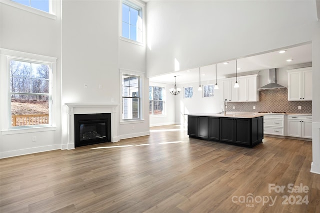 kitchen featuring pendant lighting, plenty of natural light, wall chimney exhaust hood, and light hardwood / wood-style flooring