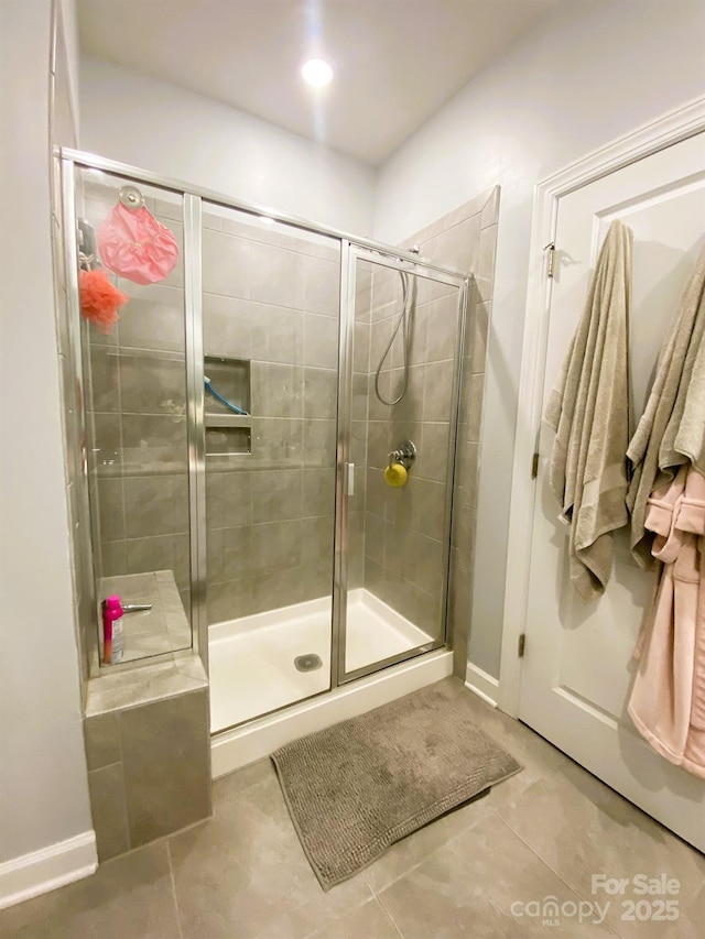 bathroom with a shower with door and tile patterned floors