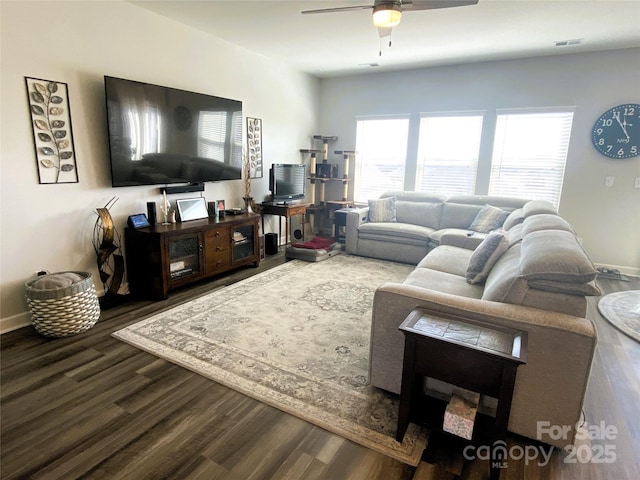 living room featuring a ceiling fan, visible vents, baseboards, and wood finished floors