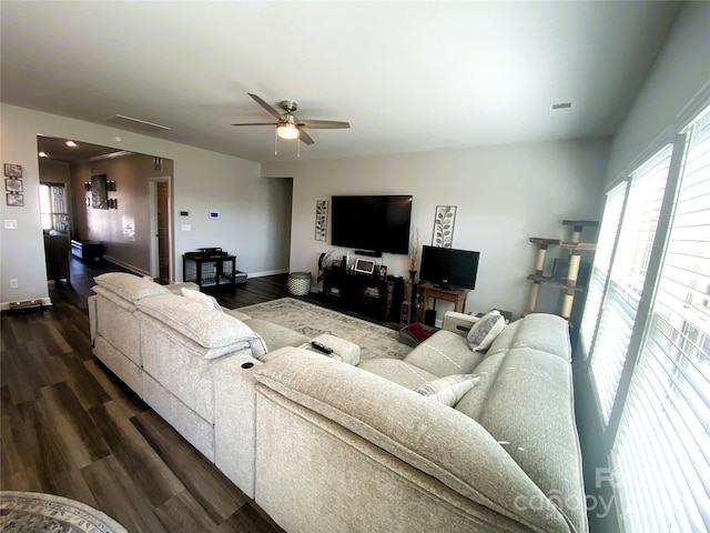 living area with a healthy amount of sunlight, dark wood-style floors, baseboards, and a ceiling fan