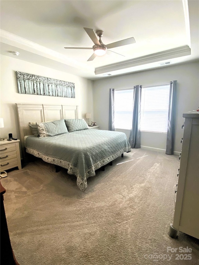 bedroom with ceiling fan, carpet flooring, visible vents, baseboards, and a tray ceiling