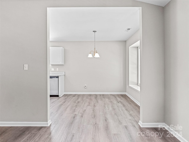 unfurnished dining area featuring light hardwood / wood-style floors and a chandelier