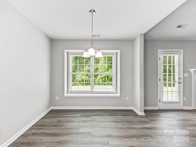 unfurnished dining area featuring a wealth of natural light, hardwood / wood-style floors, and a chandelier