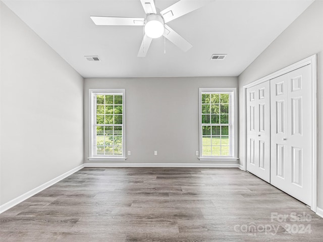 unfurnished room with ceiling fan, a skylight, a healthy amount of sunlight, and hardwood / wood-style floors