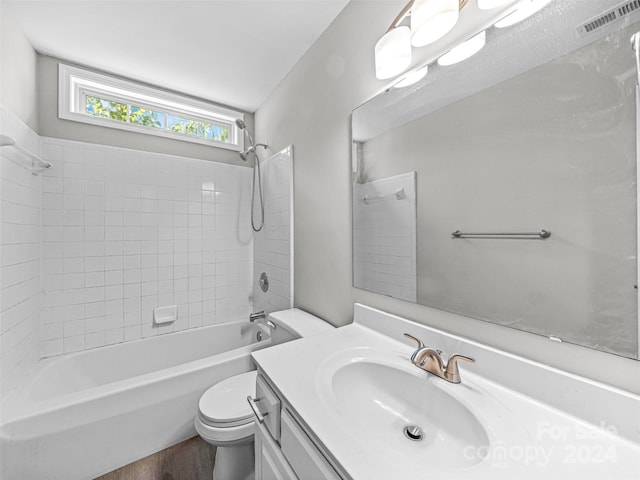 full bathroom with hardwood / wood-style floors, washtub / shower combination, toilet, and vanity