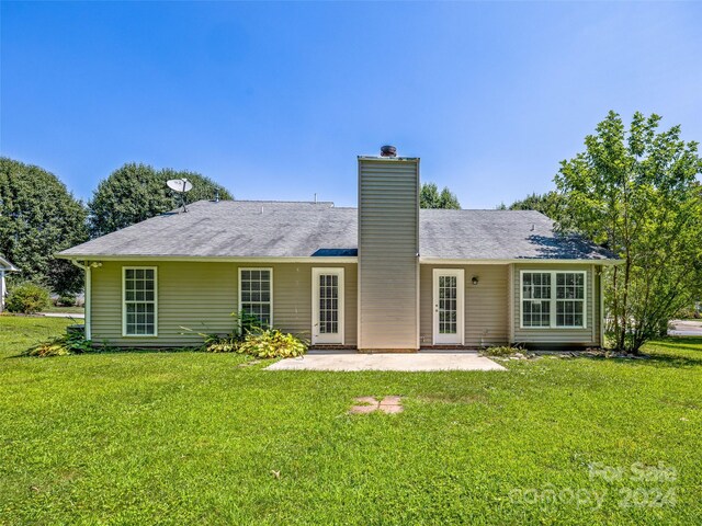 rear view of house with a patio and a lawn