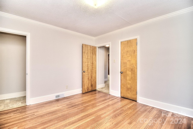 unfurnished bedroom with crown molding, light wood-type flooring, and a textured ceiling