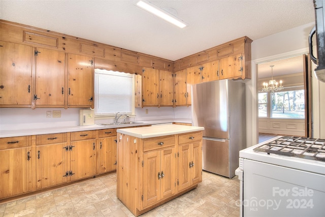 kitchen with a center island, sink, a notable chandelier, white range oven, and stainless steel fridge