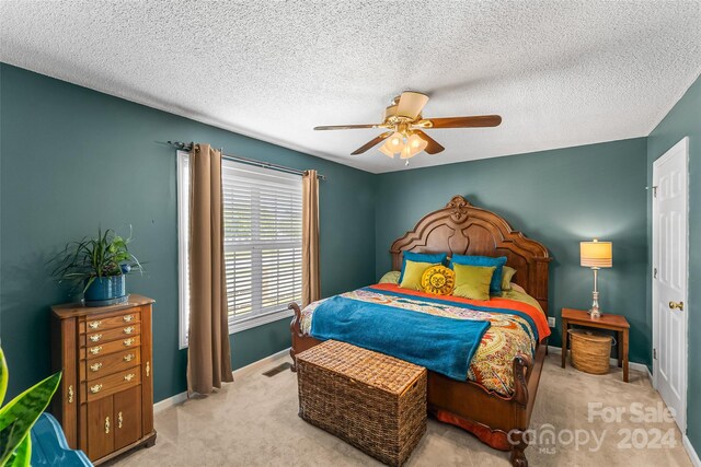 bedroom featuring ceiling fan, light carpet, and a textured ceiling