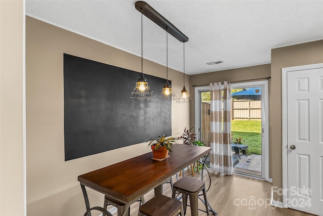 dining room featuring a textured ceiling, visible vents, and wood finished floors