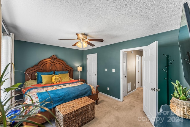 bedroom featuring a textured ceiling, ceiling fan, light colored carpet, baseboards, and a closet