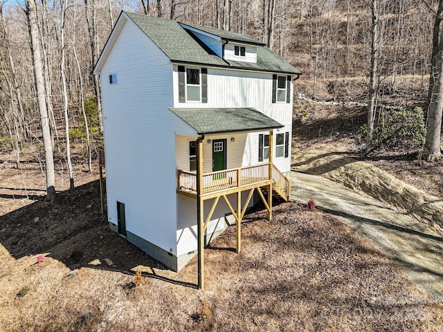 view of front of home with a deck and roof with shingles