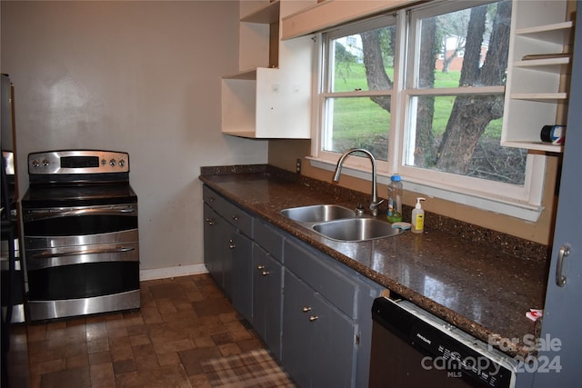 kitchen with dark stone countertops, stainless steel electric range oven, dishwasher, sink, and dark tile patterned flooring