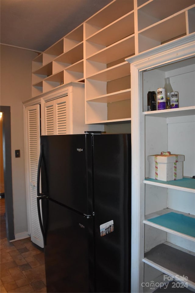 kitchen featuring black fridge and dark tile patterned flooring