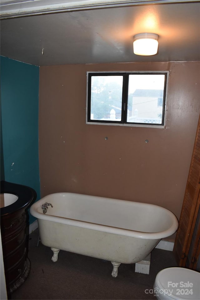 bathroom featuring a wealth of natural light, toilet, a bath, and vanity