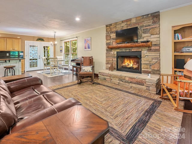 living room featuring built in features, hardwood / wood-style floors, crown molding, and a stone fireplace