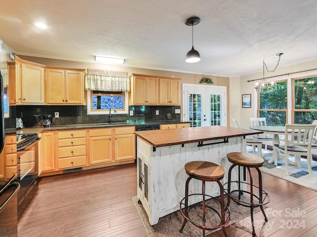 kitchen featuring light wood-type flooring, pendant lighting, a kitchen island, sink, and a breakfast bar