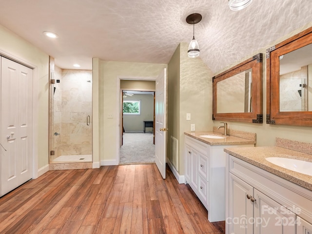 bathroom featuring vanity, a textured ceiling, hardwood / wood-style flooring, and a shower with shower door