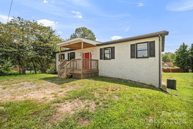 back of property featuring central AC unit and a lawn